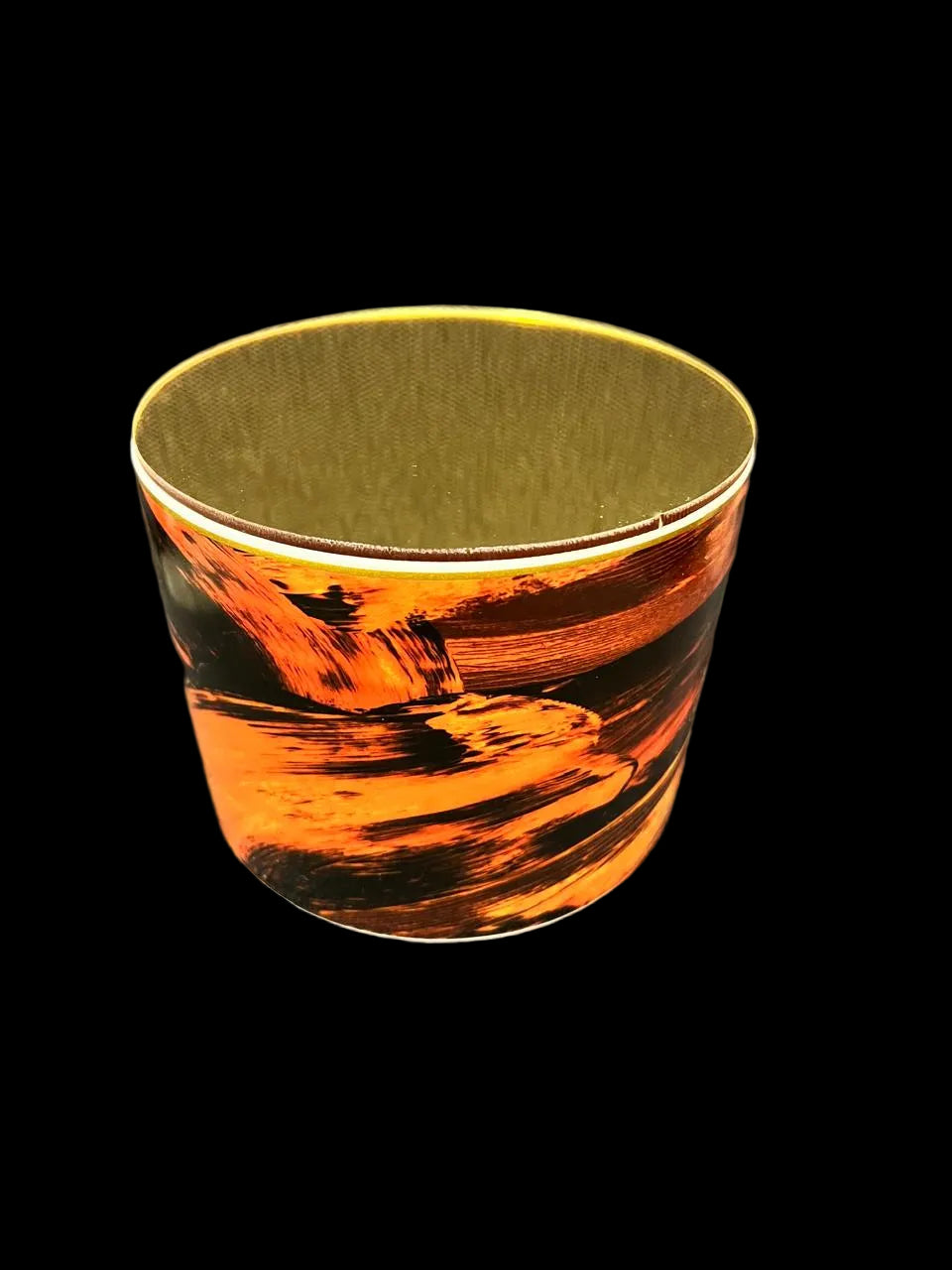 A cylindrical cup or tumbler with a printed orange and black landscape design on the outside and a plain olive-green interior, shown on a textured gray fabric background.