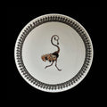 A white ceramic bowl featuring a black beaded border and a central illustration of a monkey in brown, black, and orange tones.